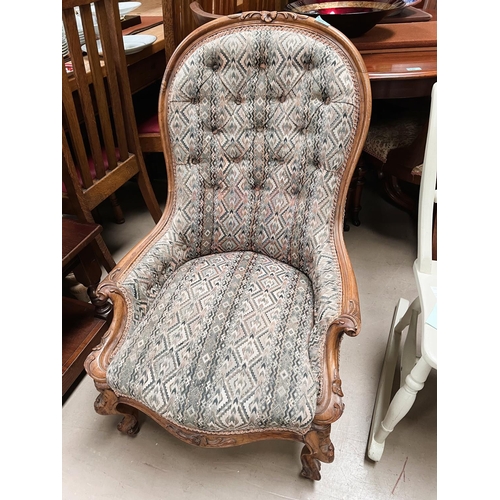 951 - A walnut framed spoon back nursing chair with carved detail with deep button back