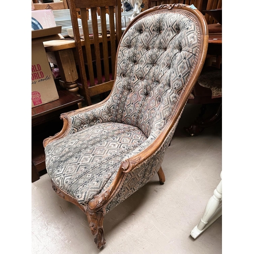 951 - A walnut framed spoon back nursing chair with carved detail with deep button back