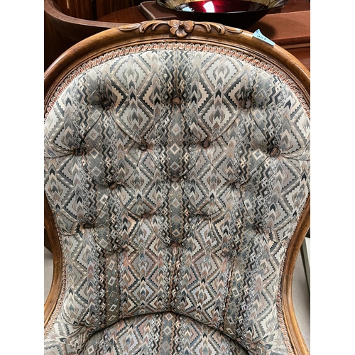 951 - A walnut framed spoon back nursing chair with carved detail with deep button back