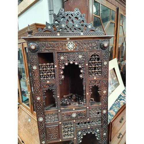 842 - A Middle Eastern full height corner cupboard with extensive carved and inlaid decoration, open shelv... 