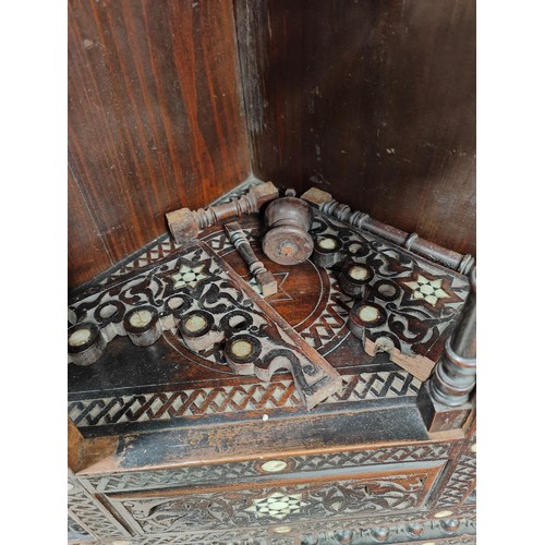 842 - A Middle Eastern full height corner cupboard with extensive carved and inlaid decoration, open shelv... 