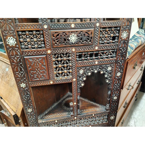 842 - A Middle Eastern full height corner cupboard with extensive carved and inlaid decoration, open shelv... 