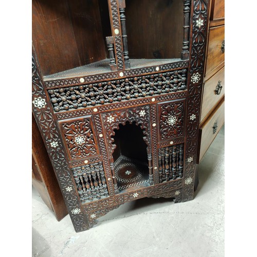 842 - A Middle Eastern full height corner cupboard with extensive carved and inlaid decoration, open shelv... 