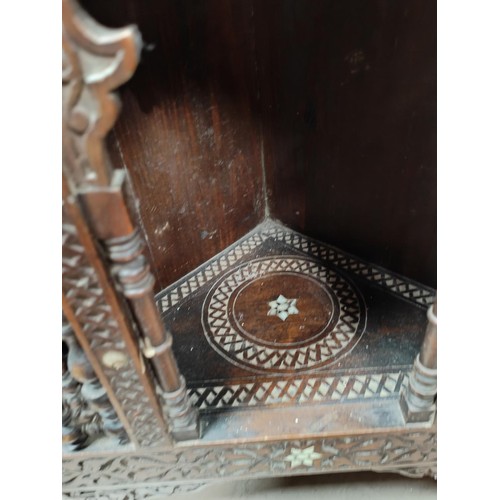 842 - A Middle Eastern full height corner cupboard with extensive carved and inlaid decoration, open shelv... 