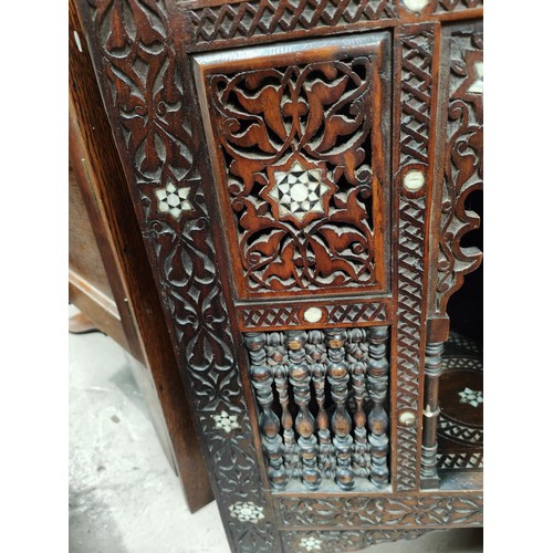 842 - A Middle Eastern full height corner cupboard with extensive carved and inlaid decoration, open shelv... 