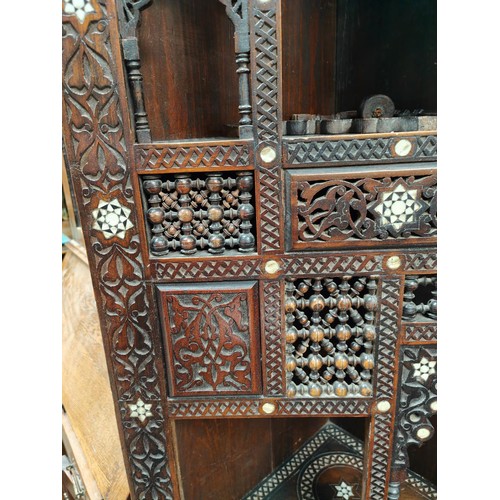 842 - A Middle Eastern full height corner cupboard with extensive carved and inlaid decoration, open shelv... 