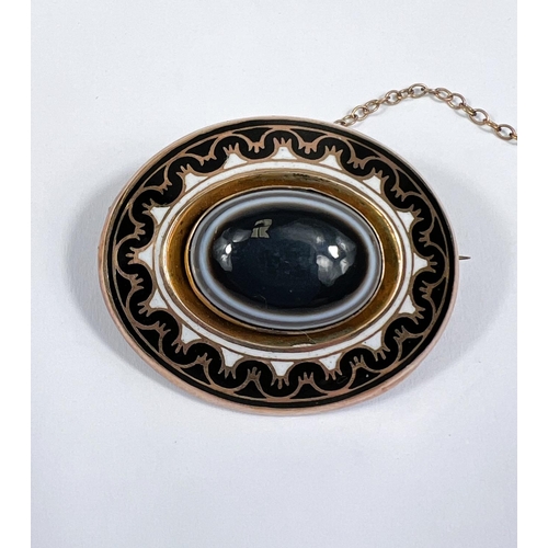 609 - A Victorian yellow metal oval mourning brooch set with  a bull's eye agate central stone, black... 