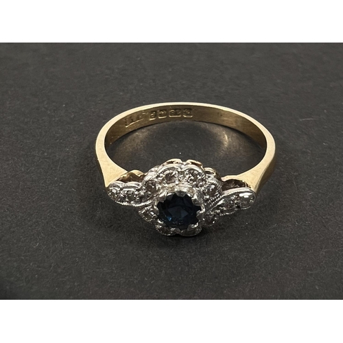 645 - An 18ct hallmarked gold ring with central sapphire and small diamonds in crossover form