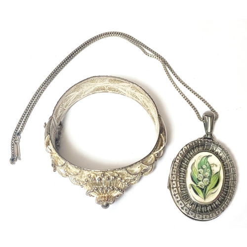 676 - An Edwardian silver locket inset floral enamel panel, white metal chain, a filigree stiff hinged ban... 