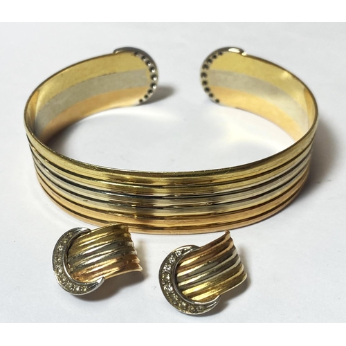 677 - A 3 colour yellow metal bangle or ridged outline, the semi circular terminals each set 9 diamonds, a... 