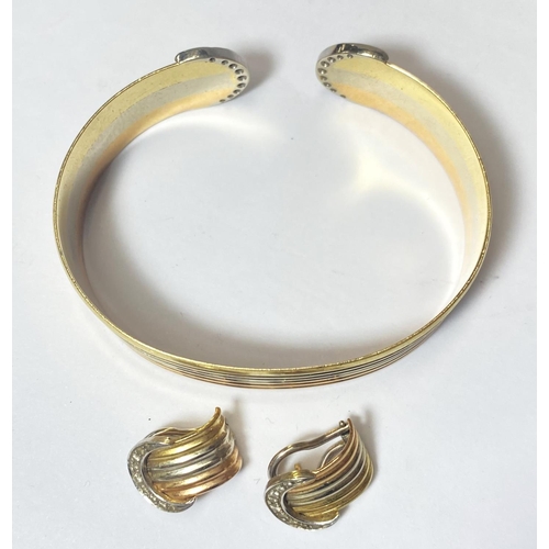 677 - A 3 colour yellow metal bangle or ridged outline, the semi circular terminals each set 9 diamonds, a... 