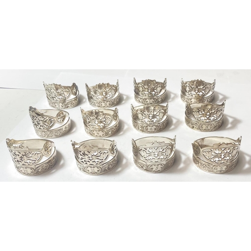 695 - A set of 12 silver plated napkin rings with pierced and etched decoration, with numbered settings fr... 