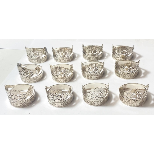 695 - A set of 12 silver plated napkin rings with pierced and etched decoration, with numbered settings fr... 