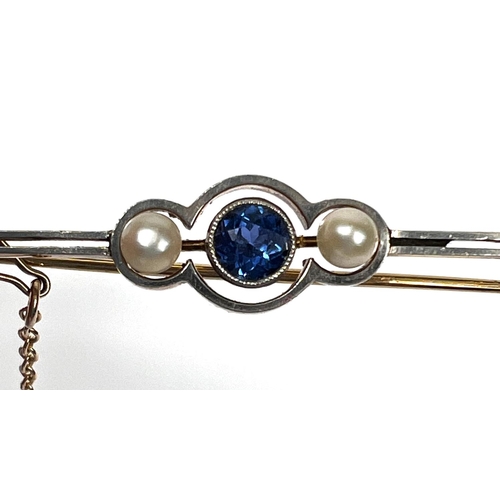 736 - A yellow metal bar brooch set with a central light blue sapphire flanked by two pearls, with safety ... 