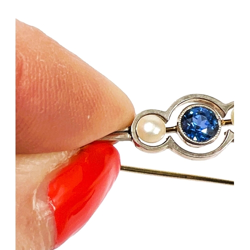 736 - A yellow metal bar brooch set with a central light blue sapphire flanked by two pearls, with safety ... 