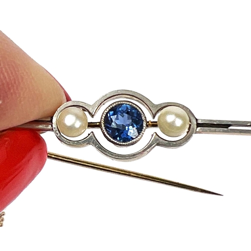 736 - A yellow metal bar brooch set with a central light blue sapphire flanked by two pearls, with safety ... 