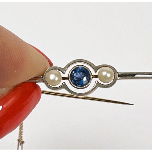 736 - A yellow metal bar brooch set with a central light blue sapphire flanked by two pearls, with safety ... 