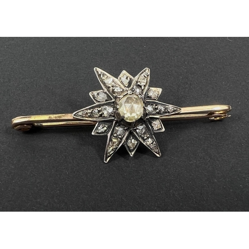 738 - A yellow metal bar brooch with central star shaped design set with central tinted multi-faceted old ... 