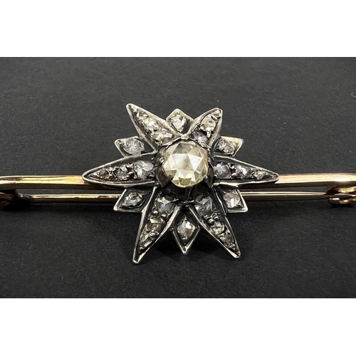 738 - A yellow metal bar brooch with central star shaped design set with central tinted multi-faceted old ... 