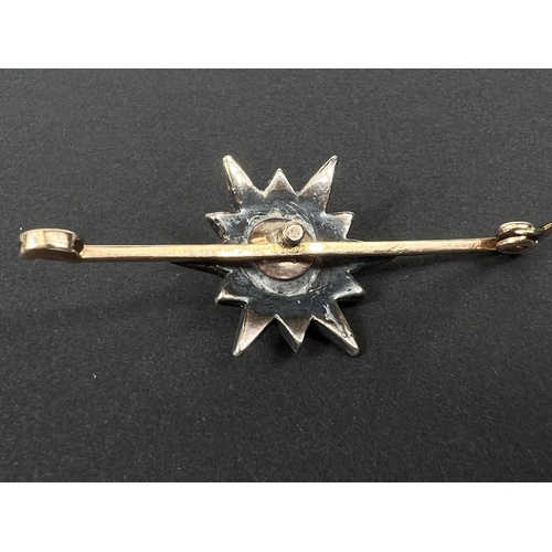 738 - A yellow metal bar brooch with central star shaped design set with central tinted multi-faceted old ... 