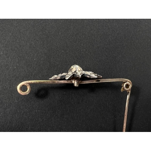 738 - A yellow metal bar brooch with central star shaped design set with central tinted multi-faceted old ... 