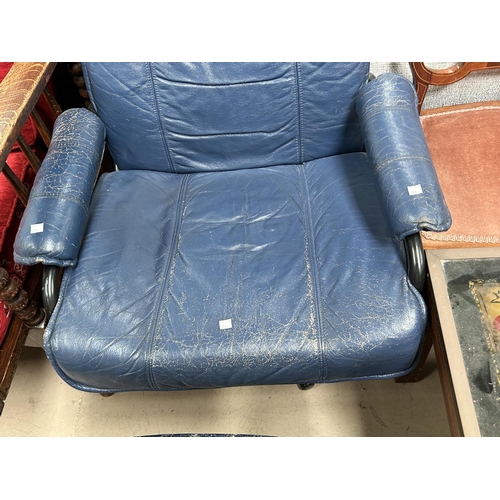 983 - A mid 20th century Danish easy chair in blue leather with footstool, label to base, black metal fram... 