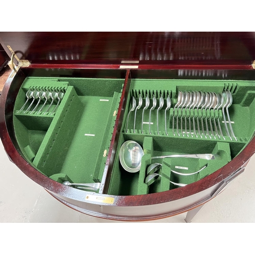 681 - A 12 setting canteen of silver plated cutlery housed in demi-lune mahogany table / cabinet