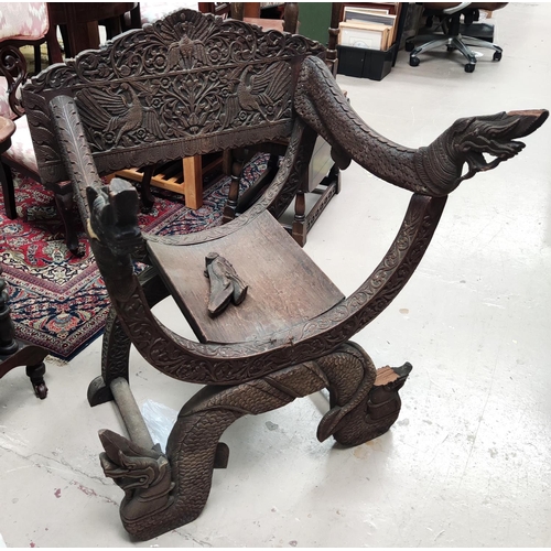 997 - A heavily carved Indonesian arm chair with rounded seat, carved serpent arms, peacock carving to the... 