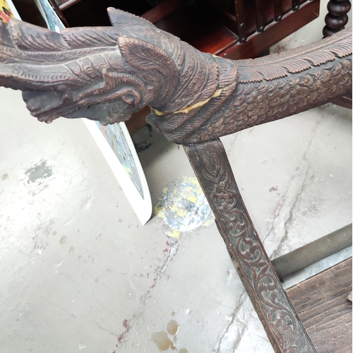 997 - A heavily carved Indonesian arm chair with rounded seat, carved serpent arms, peacock carving to the... 