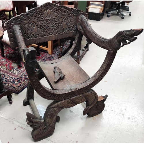 849 - A heavily carved Indonesian arm chair with rounded seat, carved serpent arms, peacock carving to the... 