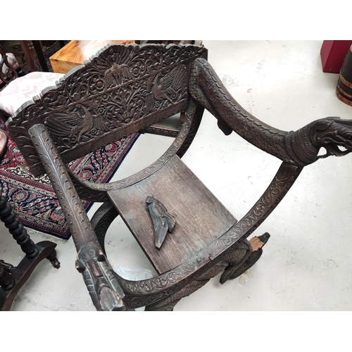 849 - A heavily carved Indonesian arm chair with rounded seat, carved serpent arms, peacock carving to the... 