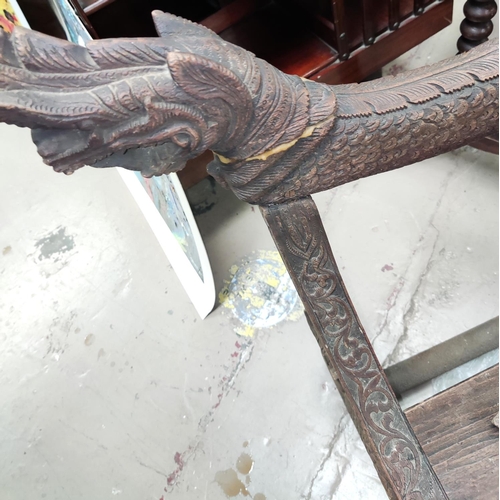 849 - A heavily carved Indonesian arm chair with rounded seat, carved serpent arms, peacock carving to the... 