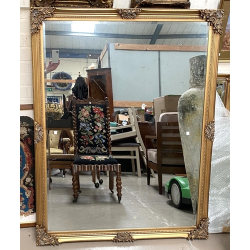 103 - A large rectangular wall mirror with bevelled edge in ornate gilt frame, length 133cm