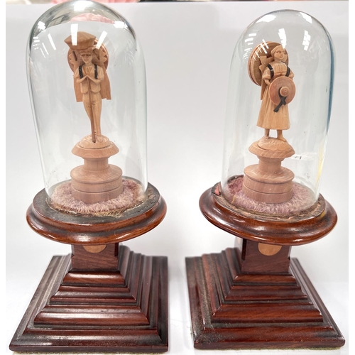62 - A 19th century pair of miniature carved figures under glass domes on stepped square bases