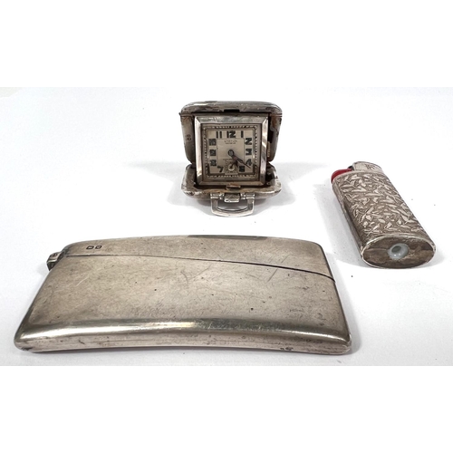 700 - A hallmarked silver card case + a travelling clock; an ornate white metal cigarette lighter.