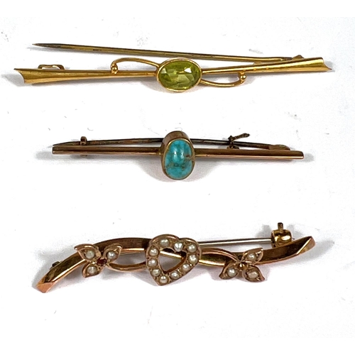 714 - A yellow metal bar brooch set with a peridot stamped 9ct  & 2 further gem set bar brooches ... 