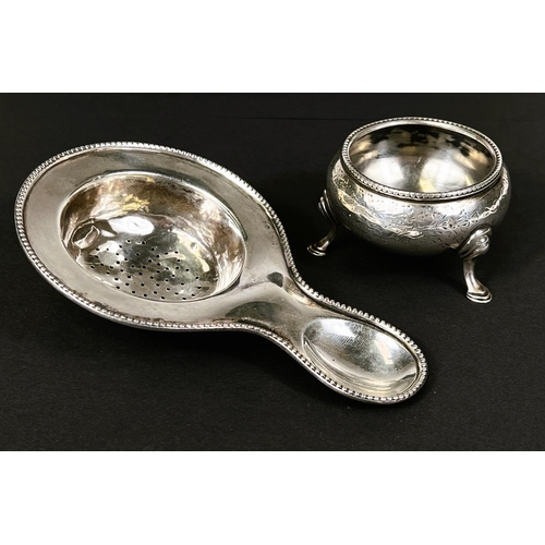 727 - A white metal tea strainer stamped 835; a hallmarked silver salt cellar, total 2.4oz