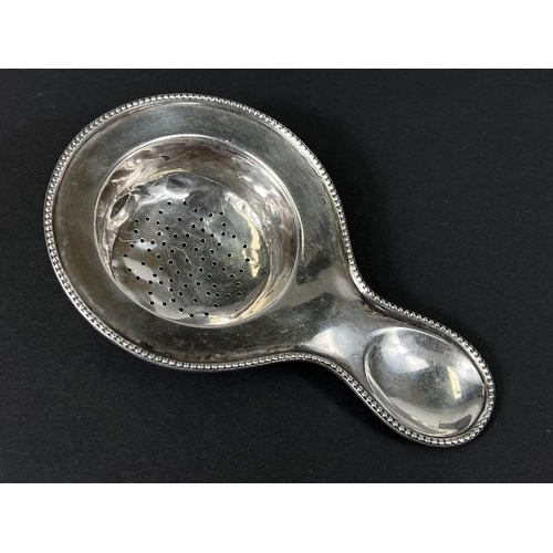 727 - A white metal tea strainer stamped 835; a hallmarked silver salt cellar, total 2.4oz