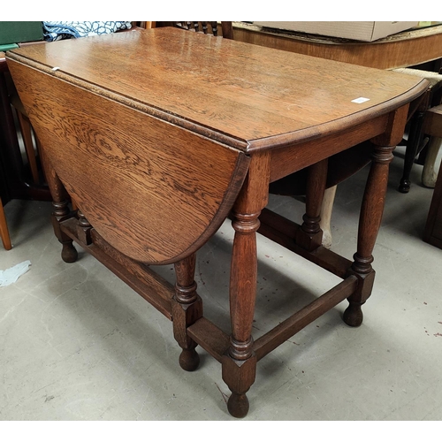 872 - A 1930's oak dining table with oval drop leaf top, on turned legs