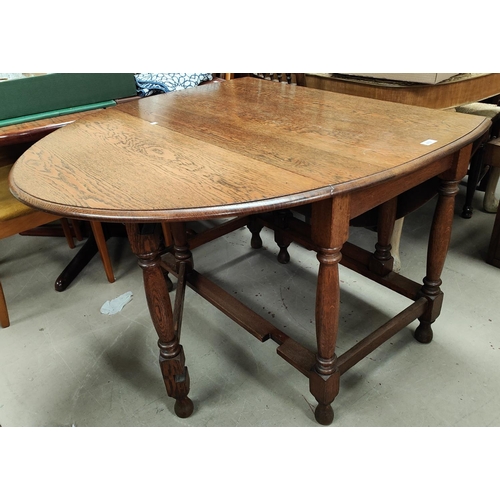 872 - A 1930's oak dining table with oval drop leaf top, on turned legs