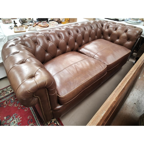 893 - A brown leather deeply buttoned back two seater settee with curved back, by Alexander and James, len... 