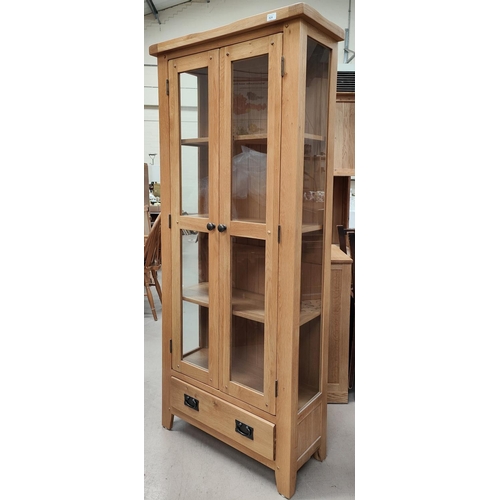 924 - A modern light oak glazed double door cabinet with drawers below 181 x 60 x 32cm