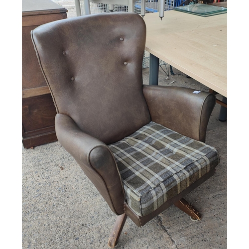 887 - A brown leather effect button wing back armchair on rotating pedestal base with stool 