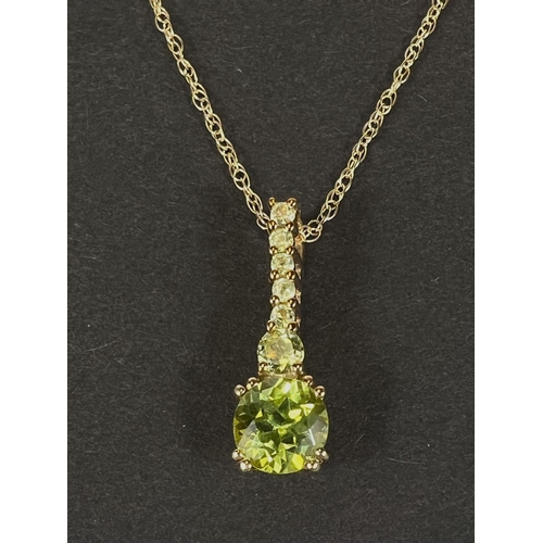 746E - An elongated peridot pendant stamped '375', on fine chain stamped '375', 1.8gm