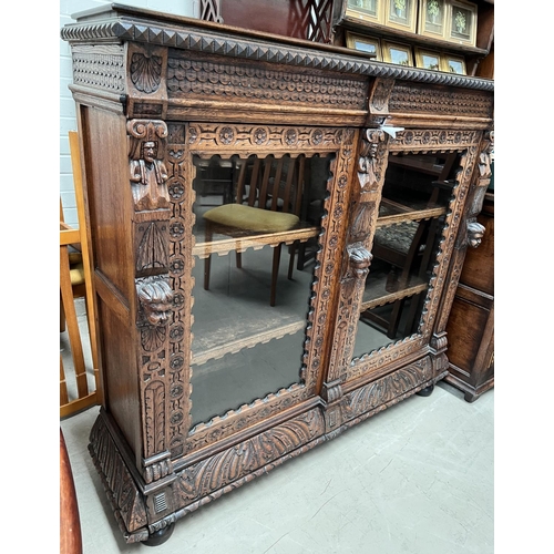 1018 - A Victorian Gothic extensively carved oak display cabinet/bookcase with shell, cherub, paws and othe... 