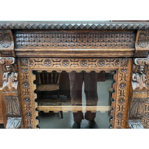 1018 - A Victorian Gothic extensively carved oak display cabinet/bookcase with shell, cherub, paws and othe... 