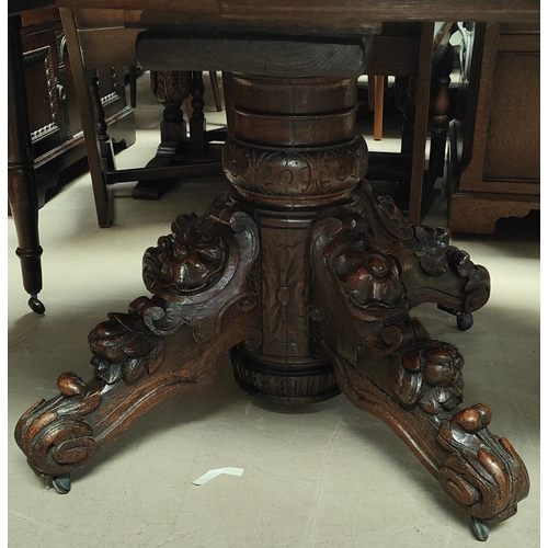 1020 - A Victorian heavily carved oak dining table with heavy three footed pedestal column rose carving cir... 