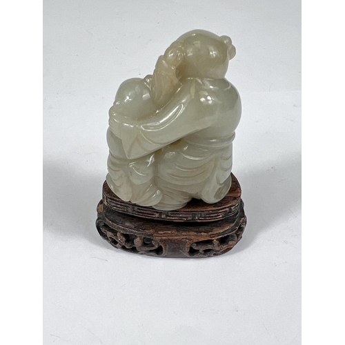 433 - A Chinese jade coloured hardstone figure of adult and child on hard wood stand, ht. 5cm