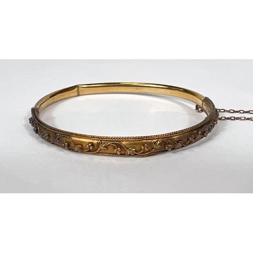 638 - A 15 carat hallmarked gold rigid hinged bangle with filigree decoration, 6.75gm (2 dents)