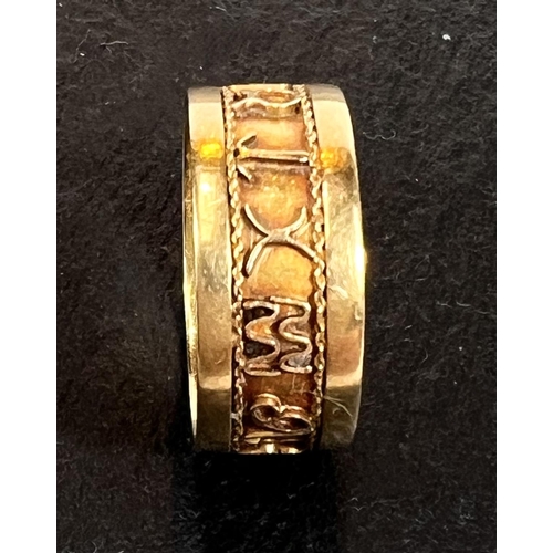 705 - A yellow metal ring with a band of relief hieroglyphs/characters, unmarked, tests as circa 18ct, siz... 